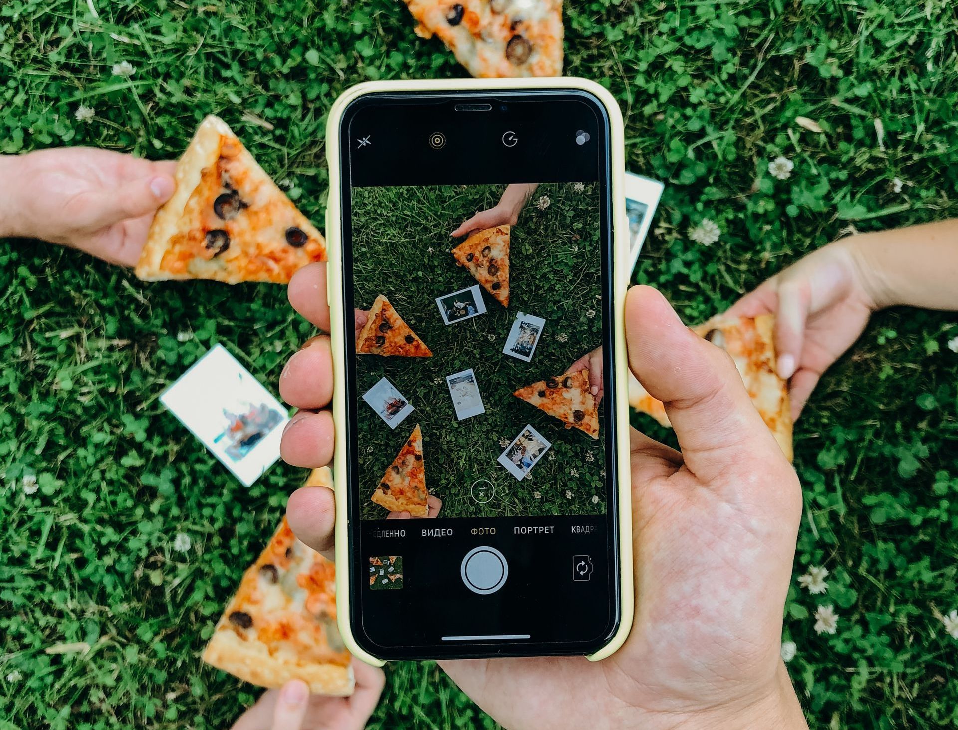 A person is taking a picture of pizza slices with a cell phone.