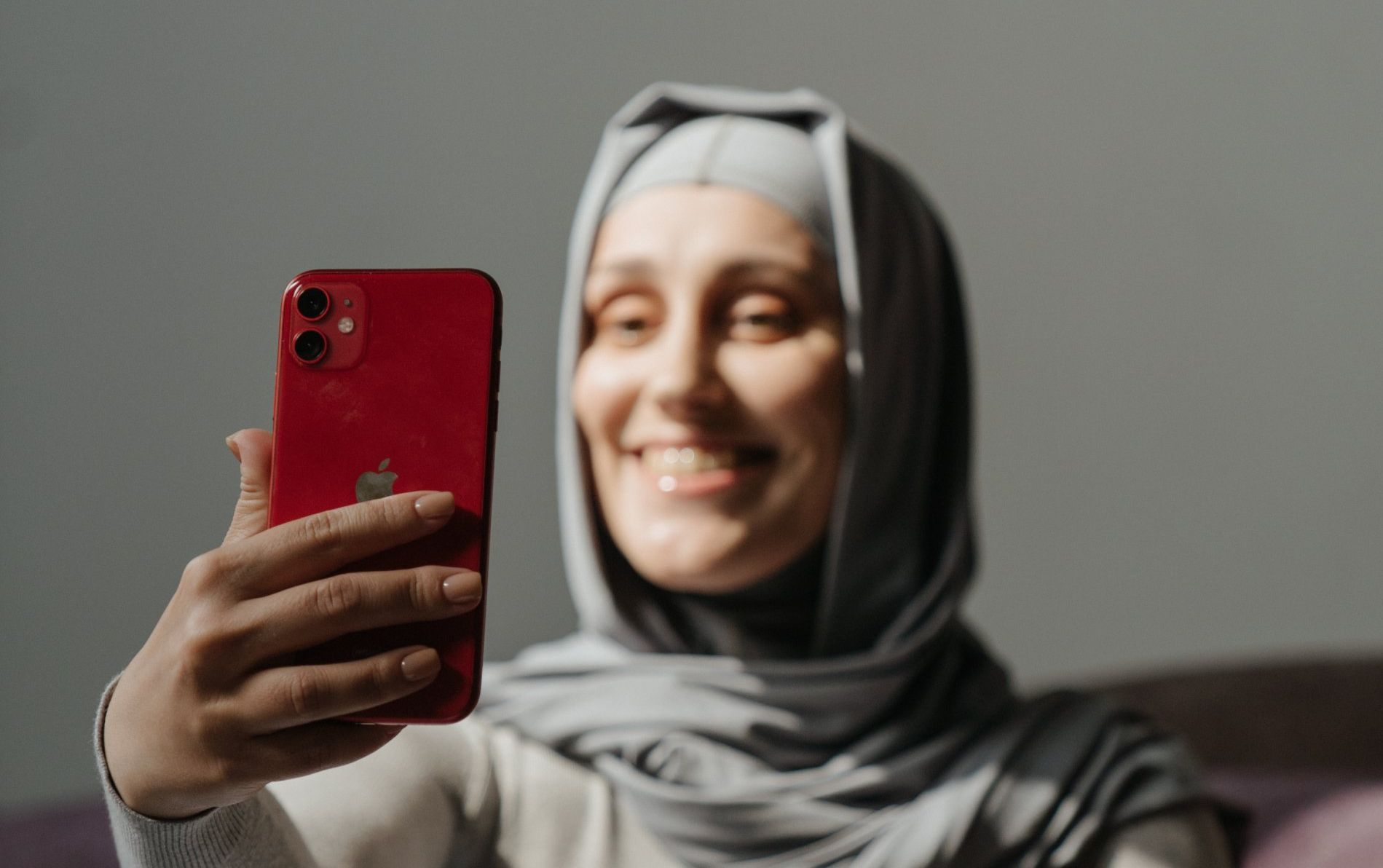 A woman in a hijab is taking a selfie with her phone.