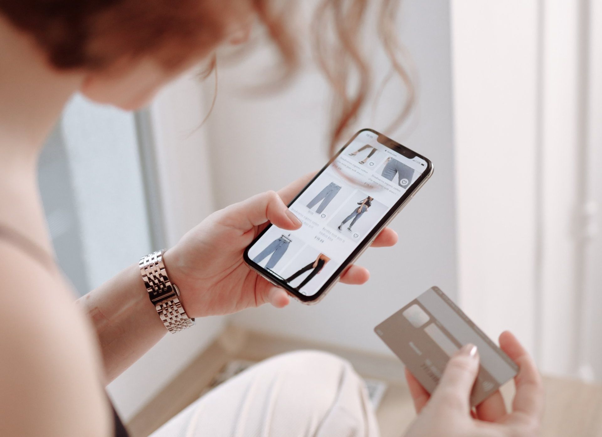 A woman is holding a credit card and a cell phone.