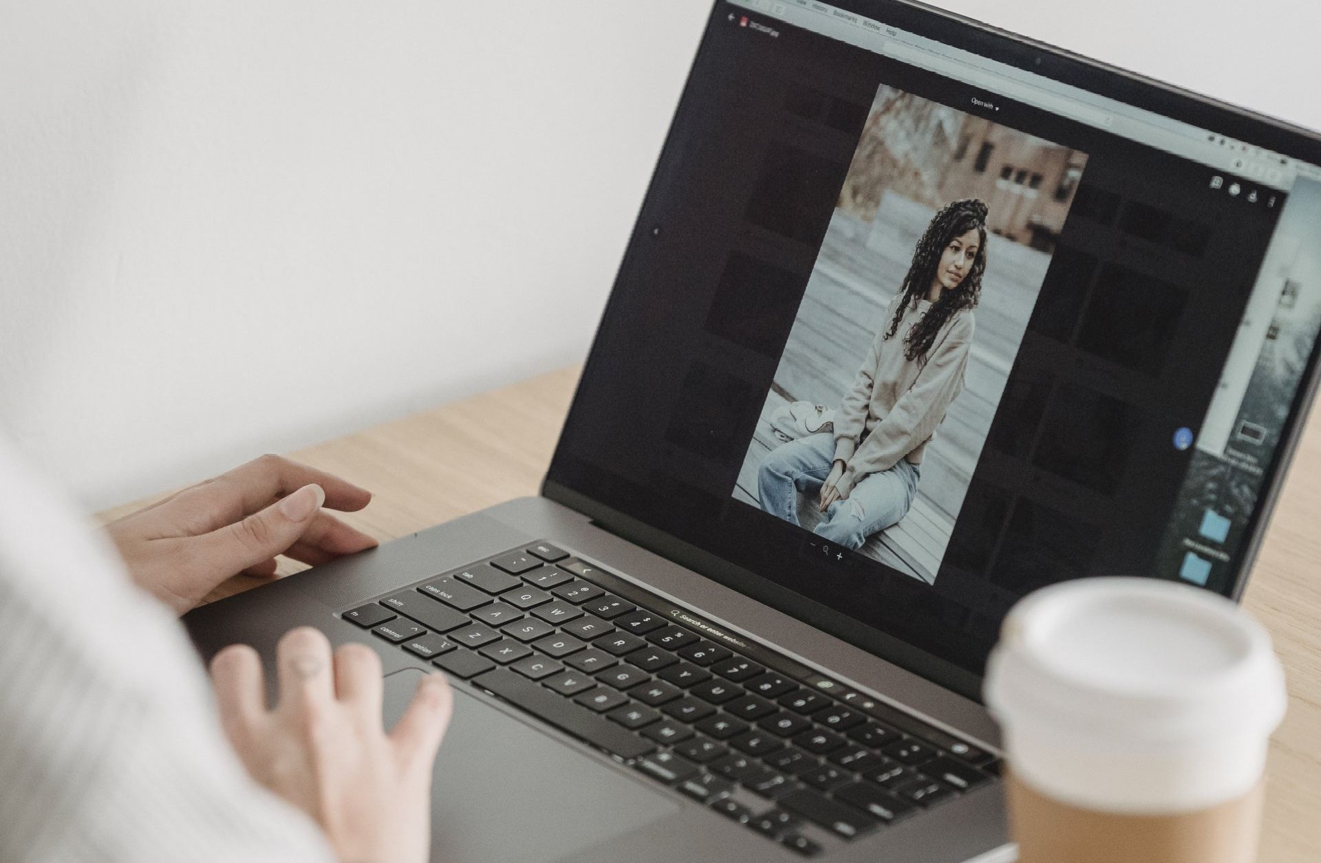 A person is using a laptop computer with a picture of a woman on the screen.