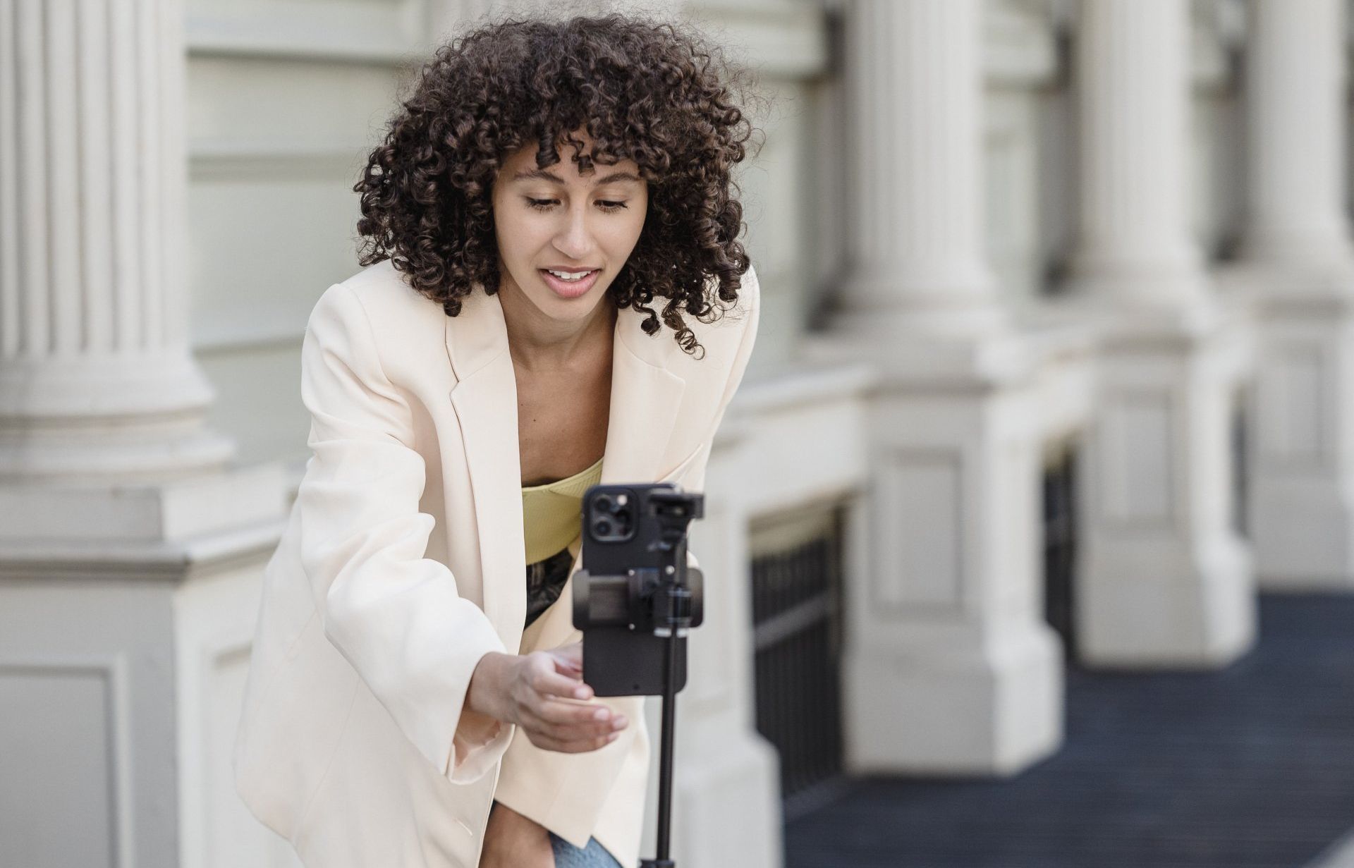 A woman is taking a picture with her cell phone on a tripod.