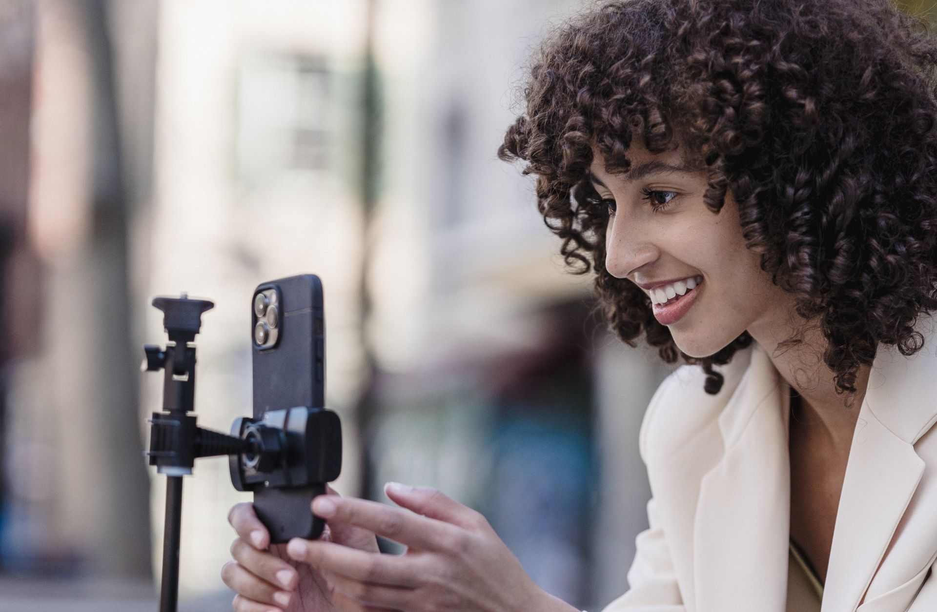 A woman is taking a picture of herself with a cell phone on a tripod.