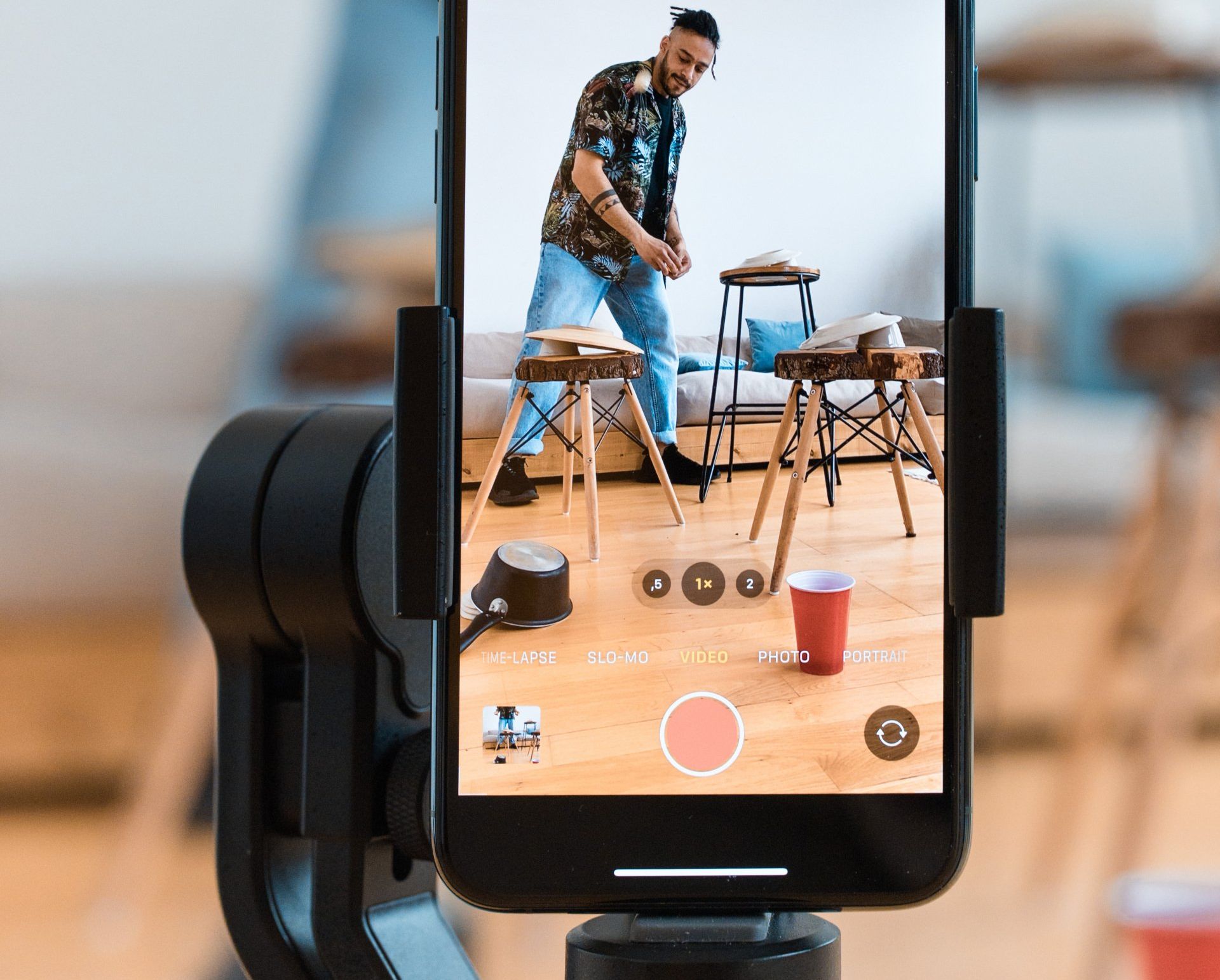 A cell phone is being used to take a picture of a man standing on a stool.