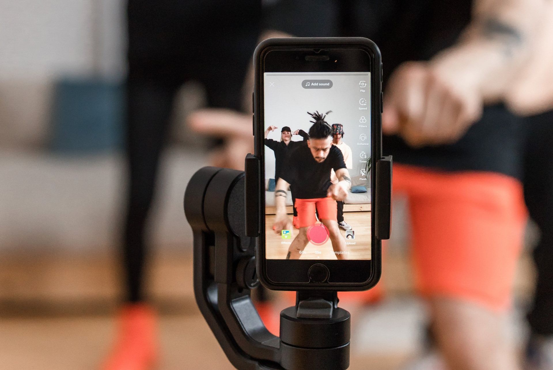 A person is taking a picture of a group of people dancing on a cell phone.