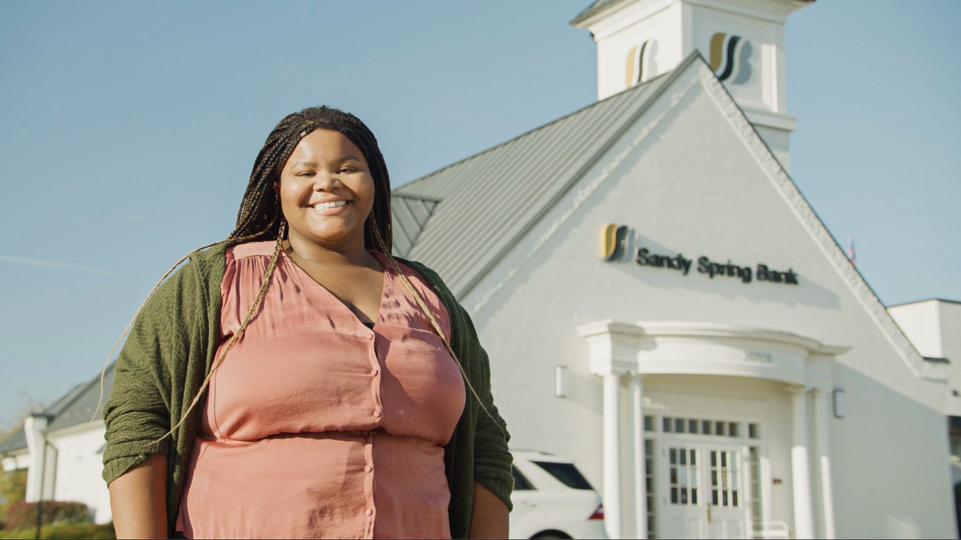 A woman is standing in front of a bank building.