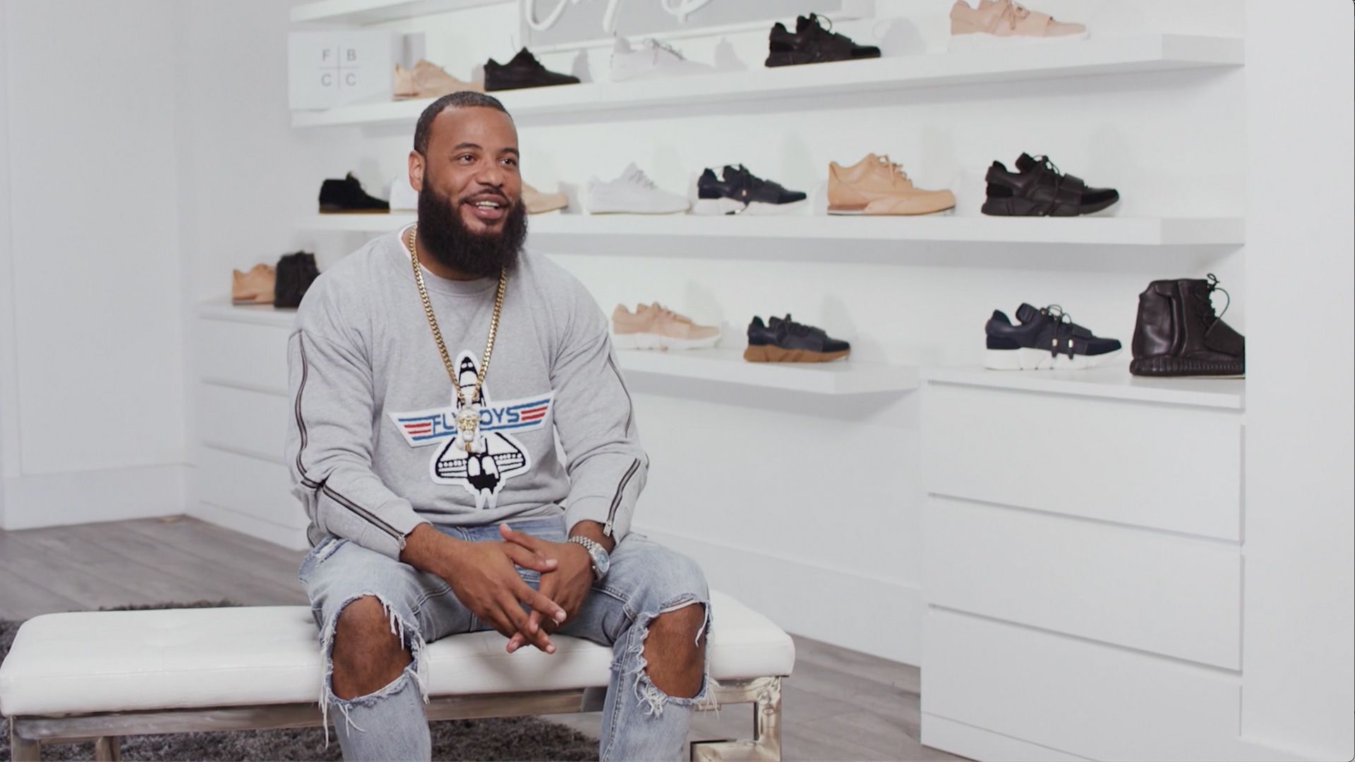 A man with a beard is sitting on a bench in a shoe store.