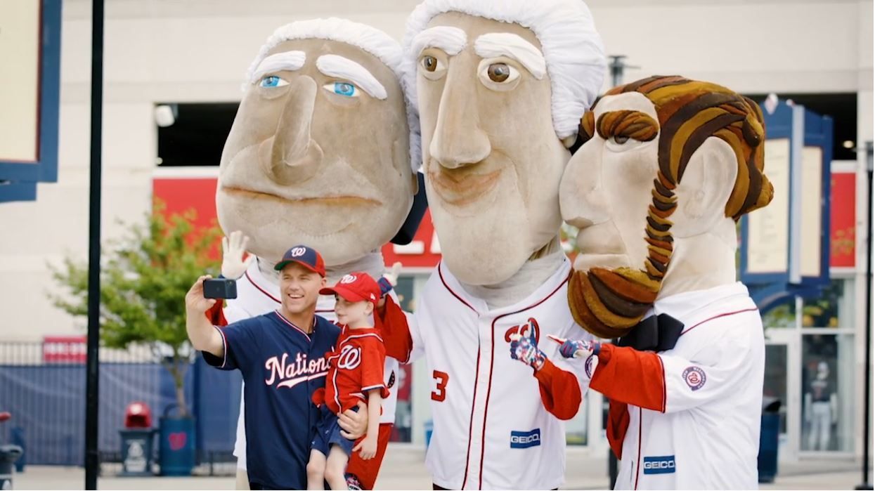 A man is taking a selfie with three mascots.