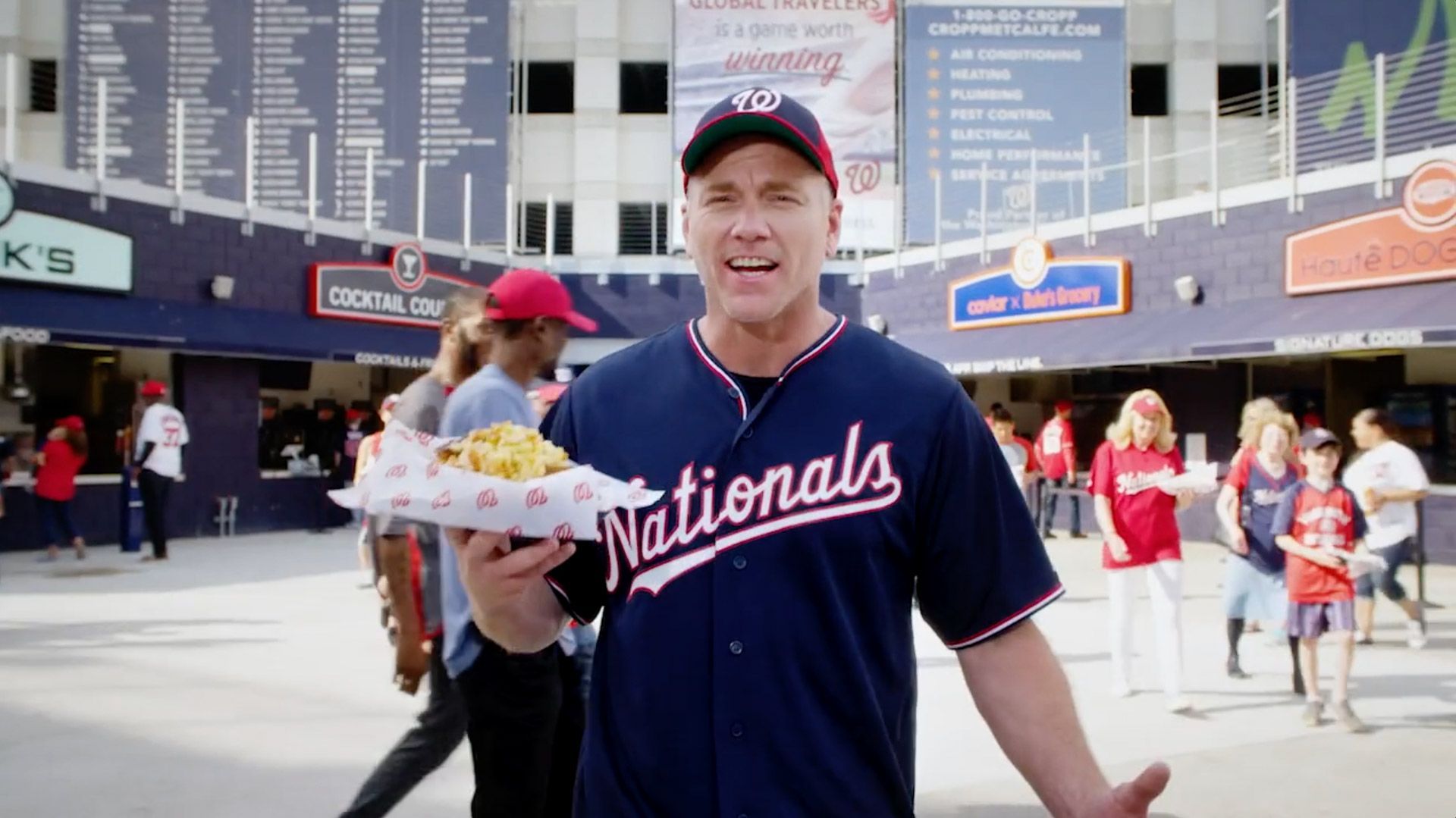 A man in a nationals jersey is holding a tray of food.