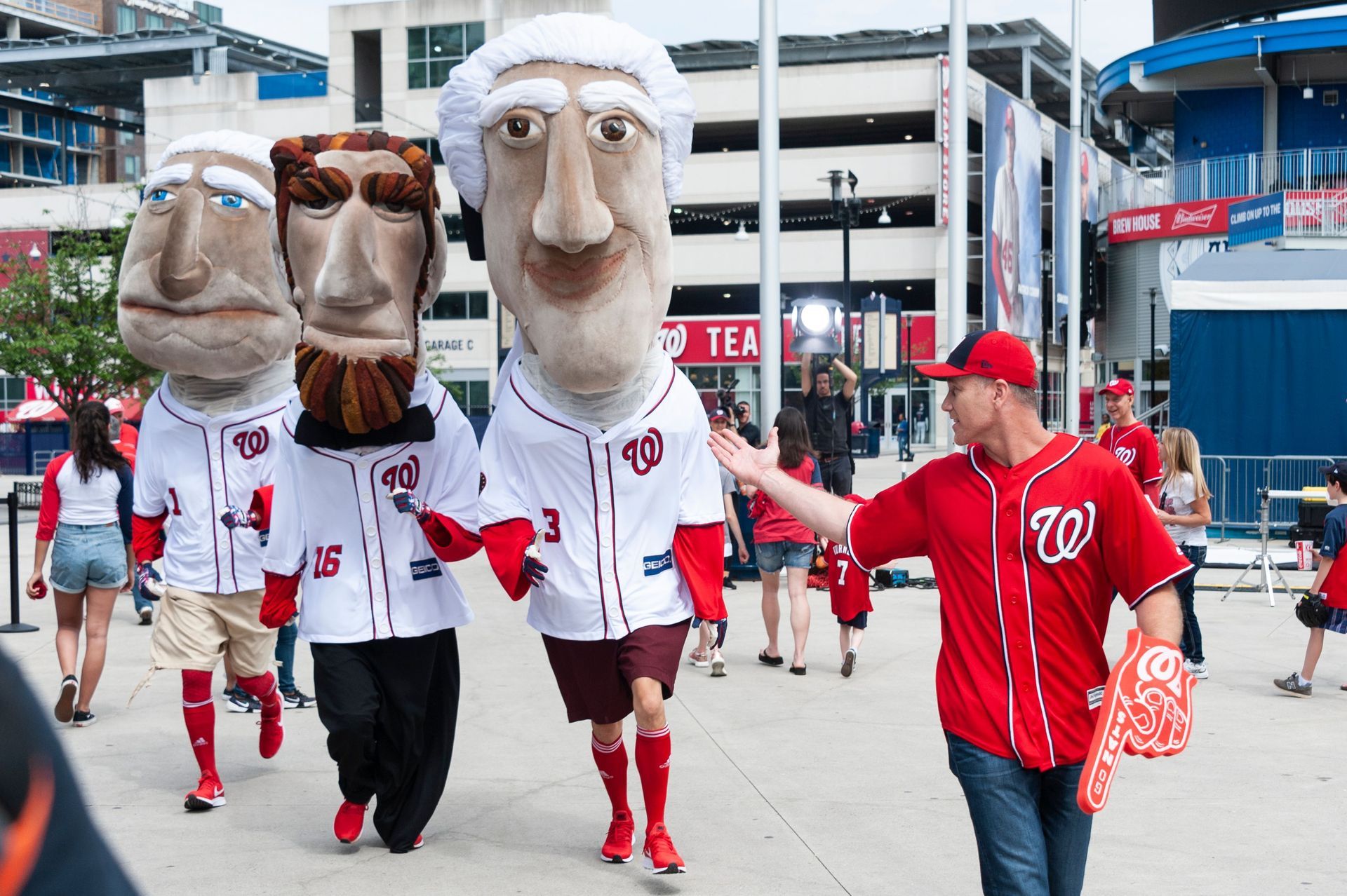 A man in a washington nationals jersey is walking with a group of mascots.