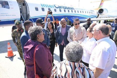 People gathered near InterCaribbean Airways plane on tarmac; various expressions and clothing.