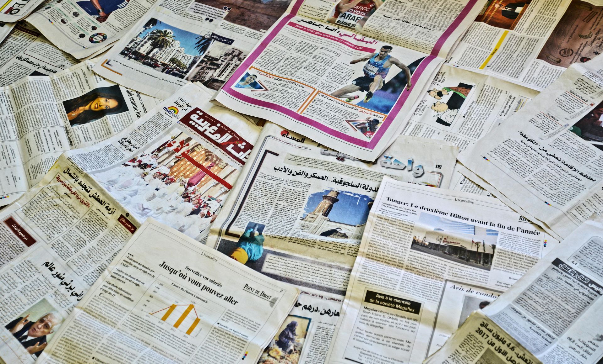 Pile of newspapers with varying content and photos.
