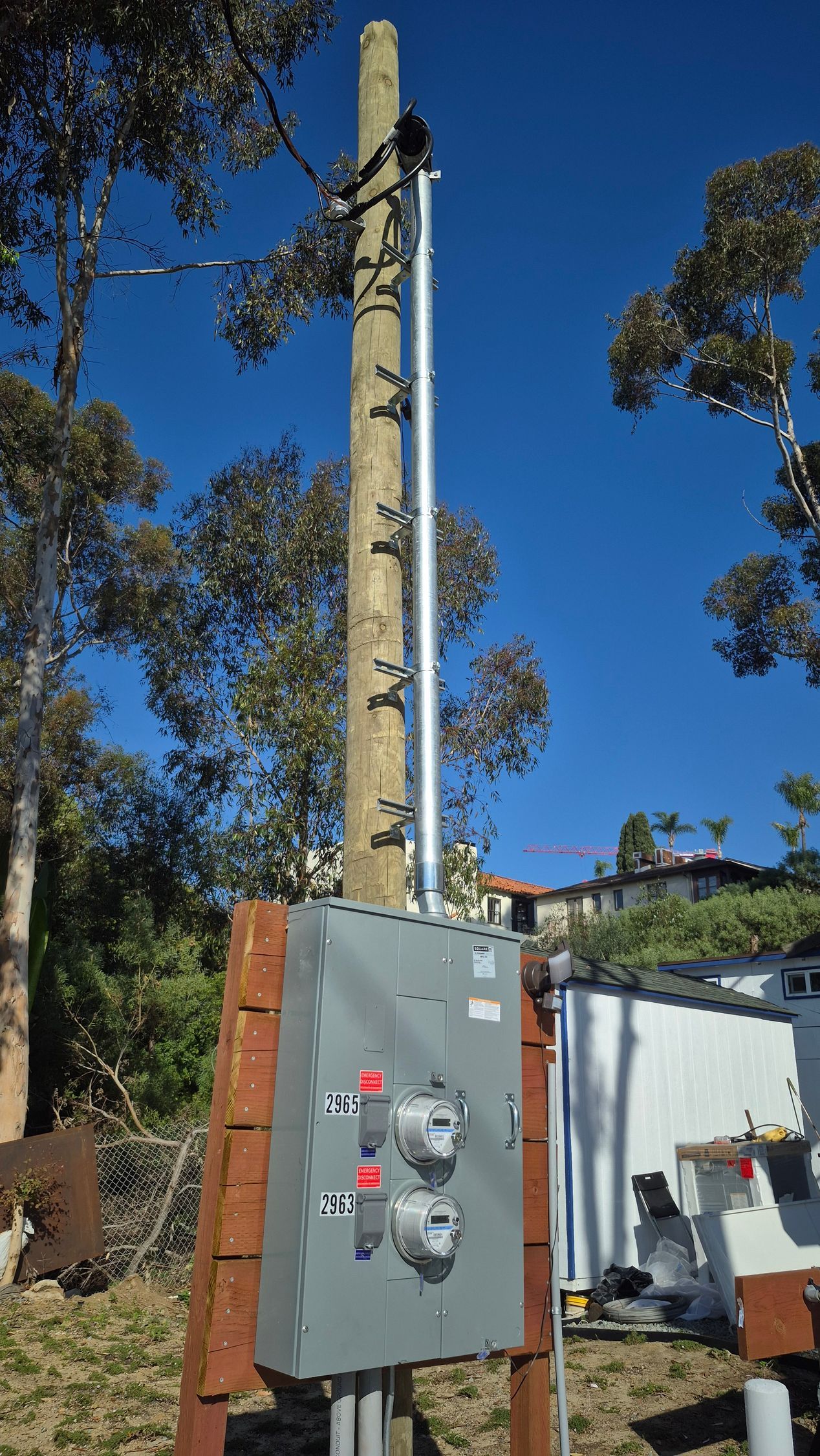 Utility pole with gray electrical control box and cables outdoors under a blue sky