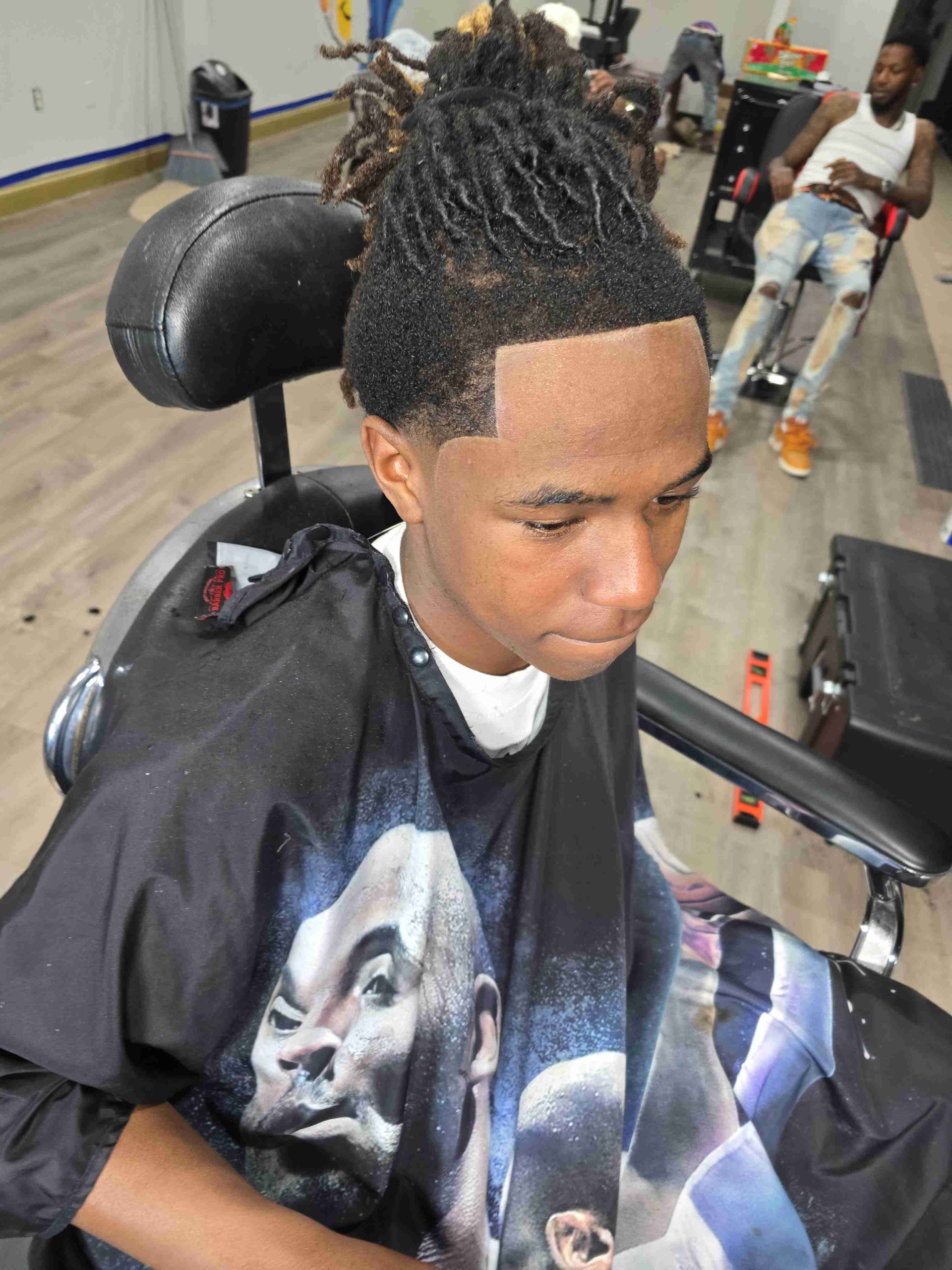 A young man is getting his hair cut at a barber shop.
