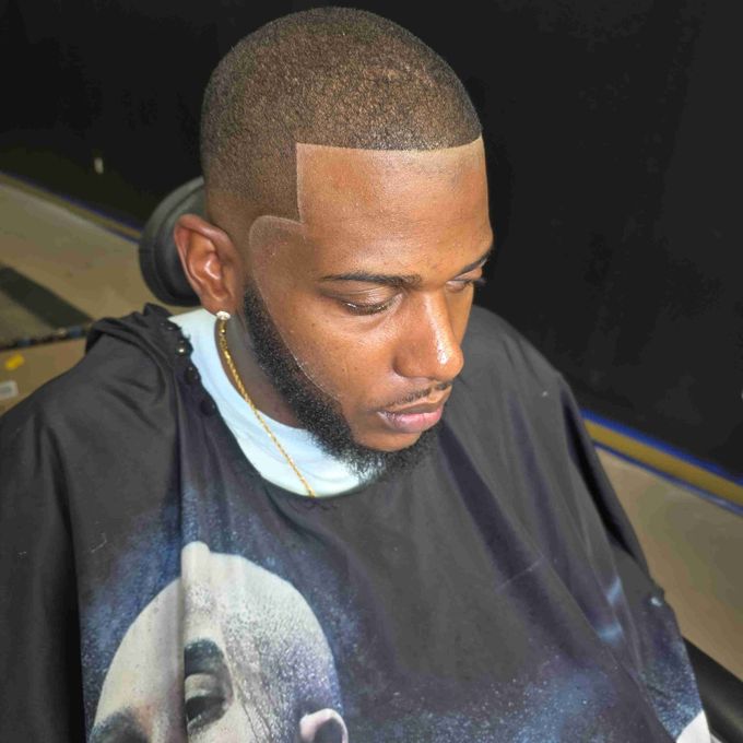 A man with a beard is getting his hair cut at a barber shop.
