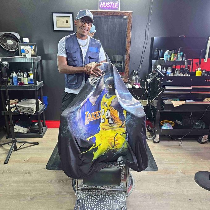 A man is cutting a man 's hair in a barber shop.