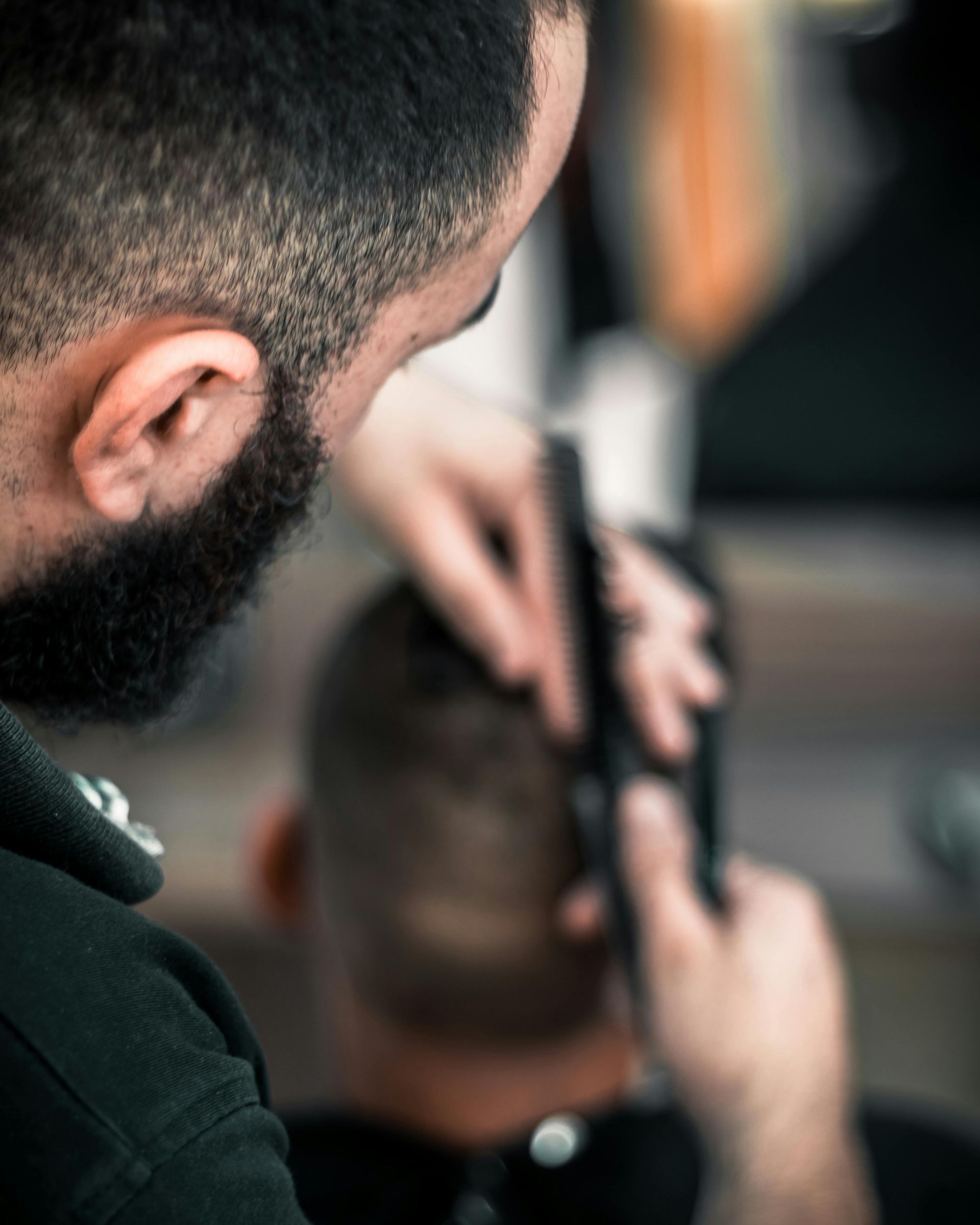 A man with a beard is getting his hair cut by a barber.