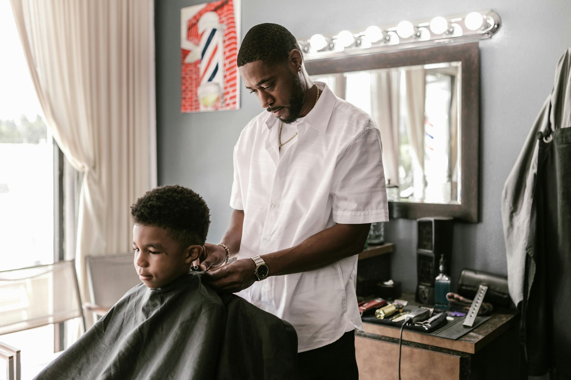 A young boy is getting his hair cut by a barber in a barber shop.