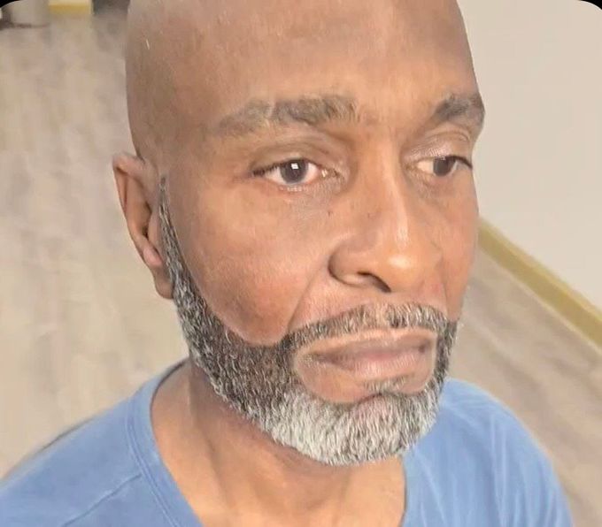 A bald man with a beard is wearing a blue shirt.