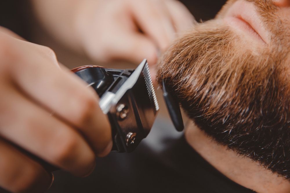 A man is getting his beard trimmed by a barber.