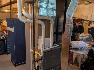 Basement utility room with a gas furnace, white PVC pipes, and exposed ductwork.