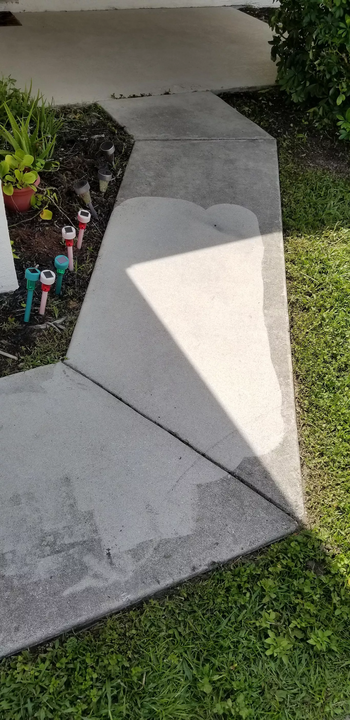 A shadow of a person is cast on a concrete walkway.