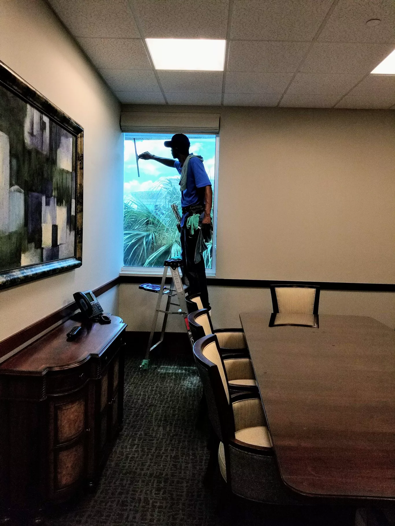 A man is cleaning a window in a conference room