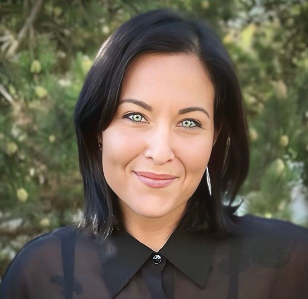 A woman wearing a black shirt and earrings is smiling for the camera.