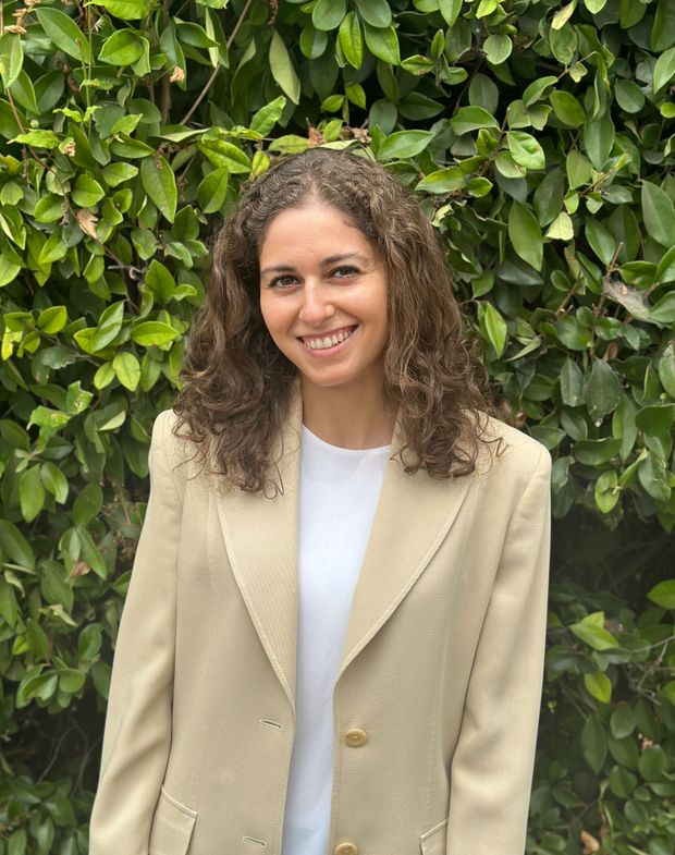 A woman wearing a white cardigan and a green shirt is smiling for the camera.