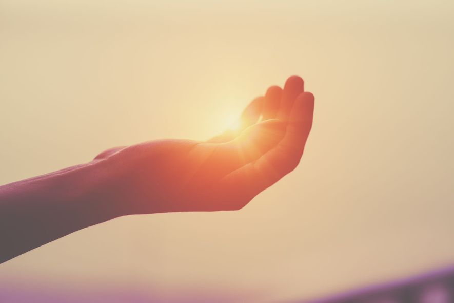 A person is holding the sun in their hand.