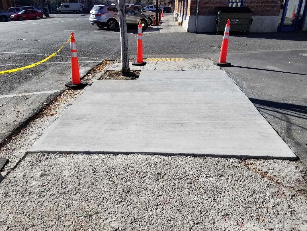 A concrete walkway with orange cones on the side of it