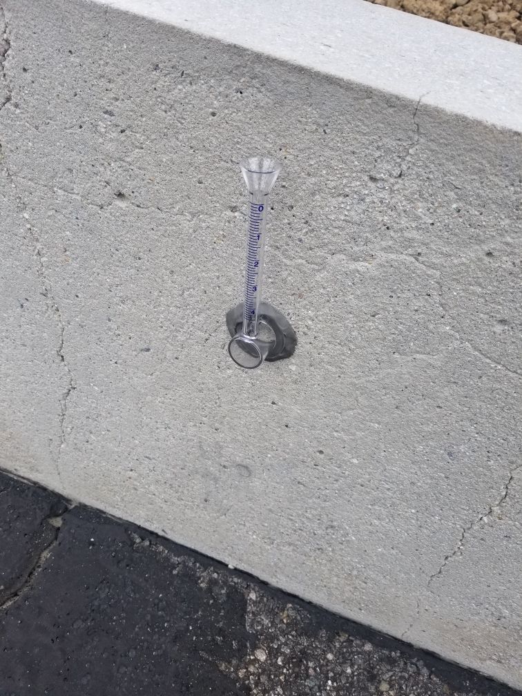 A candle is sitting on the ground next to a concrete wall.