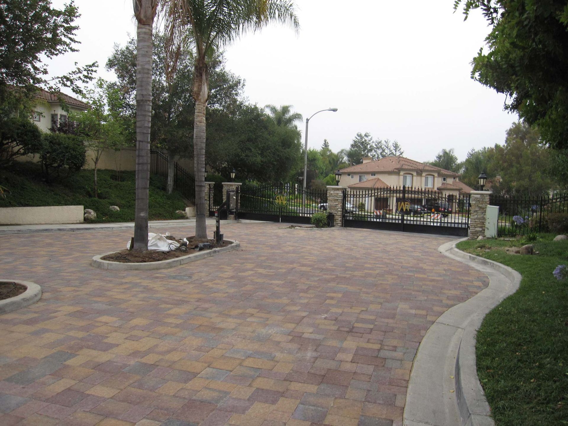 A brick driveway leading to a house with palm trees