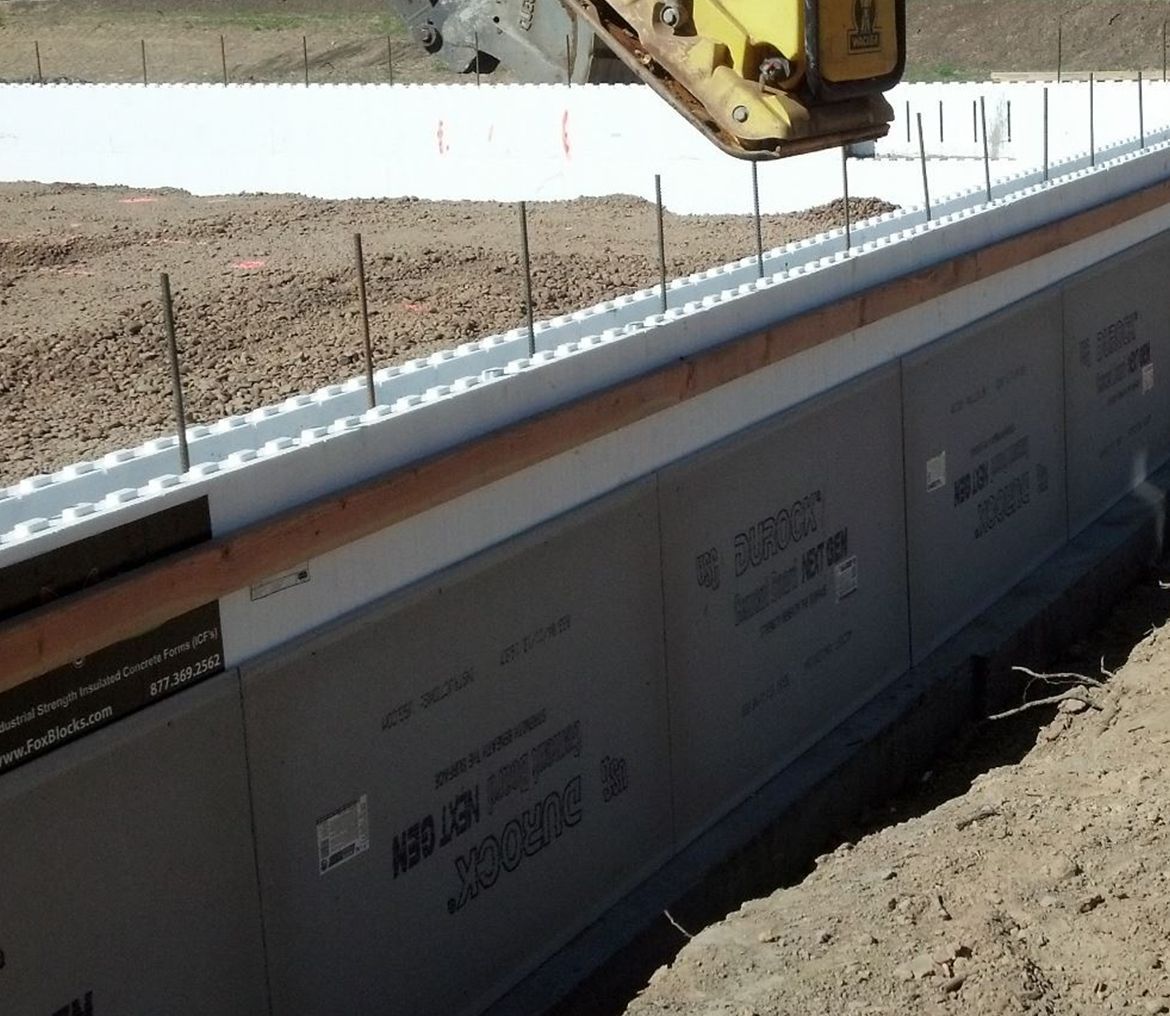 A yellow bulldozer is working on a concrete wall