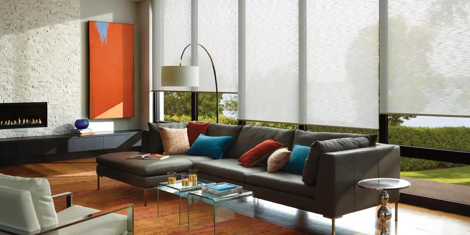 Living room with sectional sofa, orange rug, large windows, and modern art.