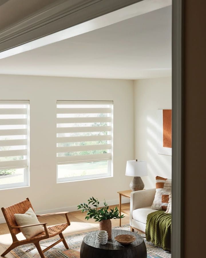 Living room with sheer window shades, a chair, sofa, and small table.