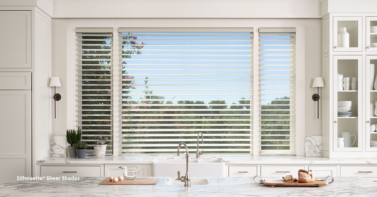 Kitchen with white cabinetry, a large window with blinds, and a marble countertop.