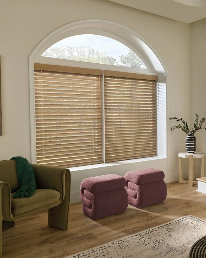 Living room with arched window, wooden blinds, seating, and decorative accents.