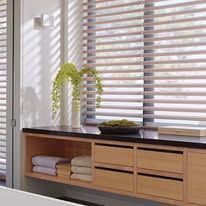 Built-in wooden shelf with towels, decorative plants, and a window with blinds.