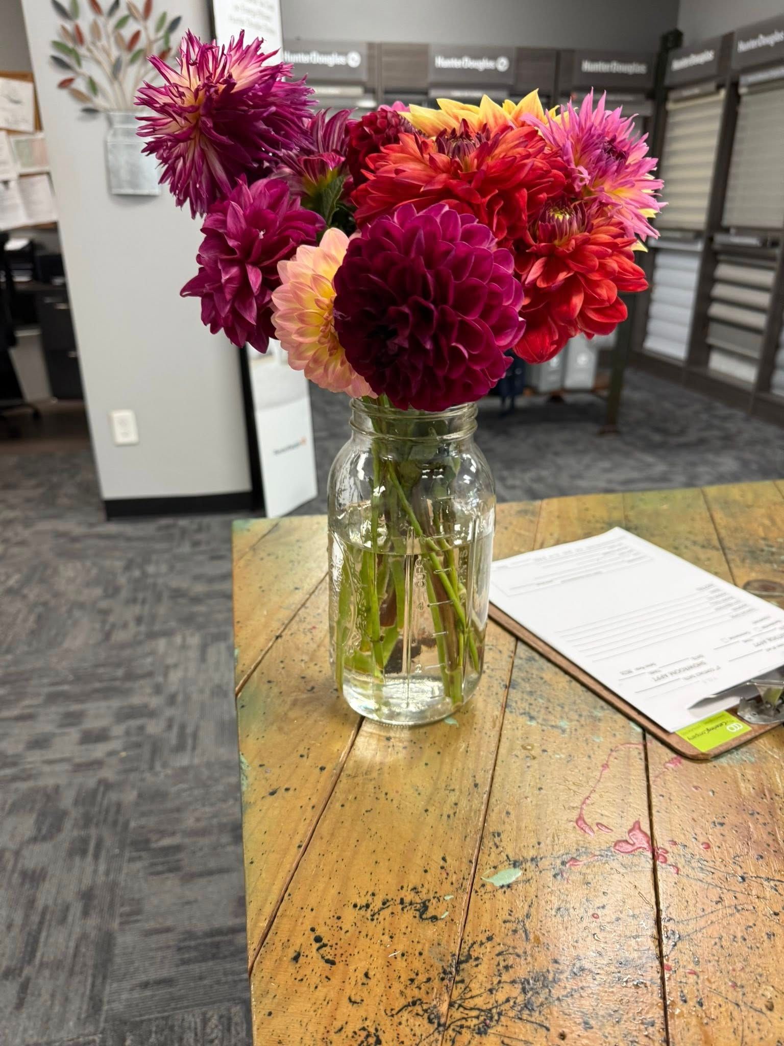 Bouquet of colorful dahlias in a mason jar vase on a wooden table.