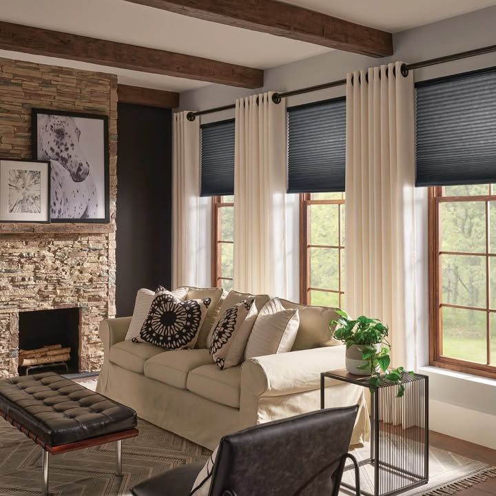 Living room with fireplace, sofa, windows, beige and black decor.