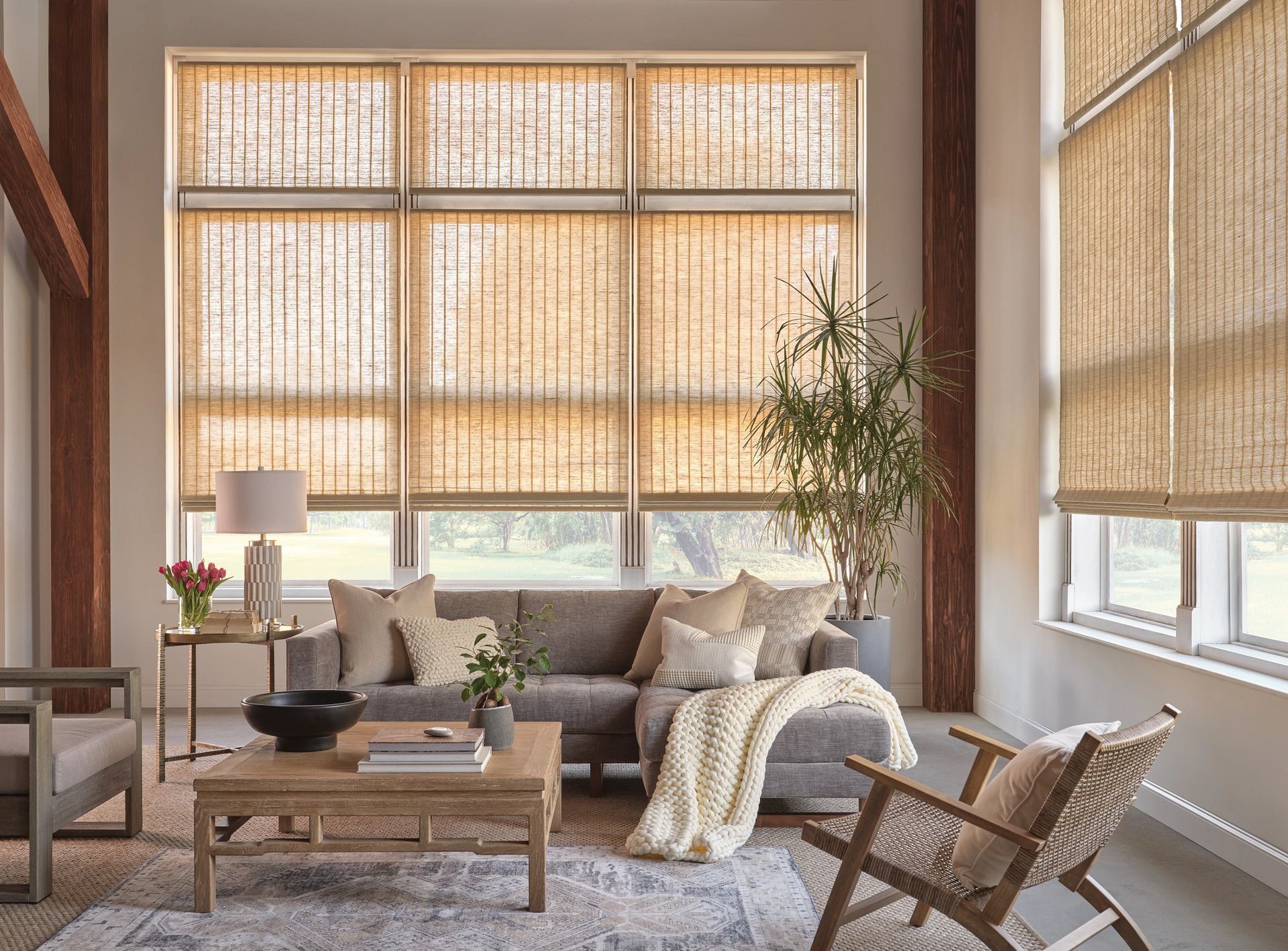 Living room with woven shades, neutral sofa, wood coffee table, and large window.