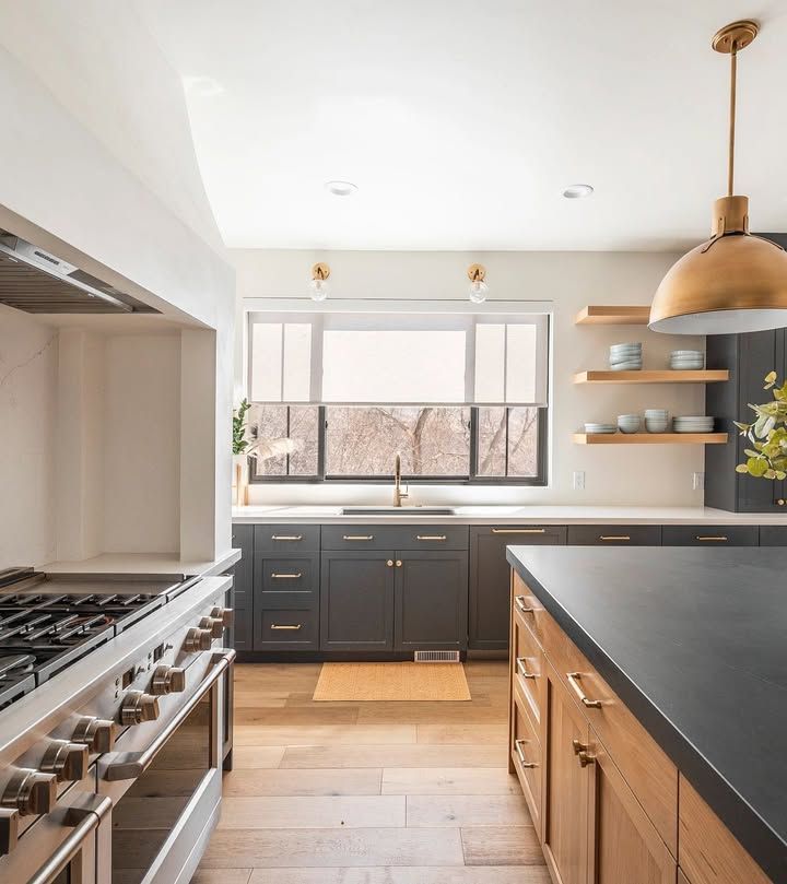 Modern kitchen with gray cabinets, wooden island, stainless steel range, and window.