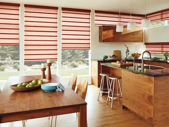 Kitchen with wooden cabinets, dining table, and windows with red blinds.