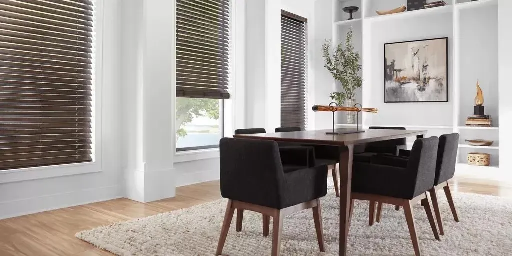 Dining room with dark wood table and chairs, brown blinds, and white built-in shelves.