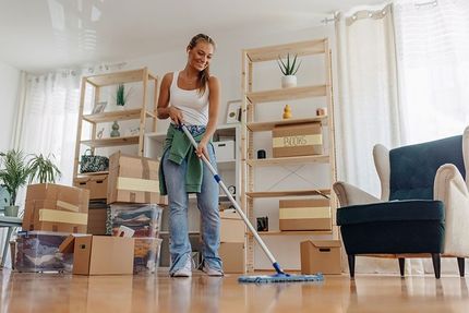 A woman is cleaning the floor of a living room with a mop.