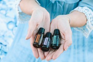 A woman is holding three bottles of essential oils in her hands.