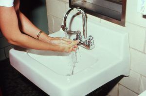 A woman is washing her hands in a bathroom sink.
