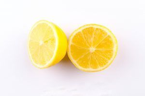 Two lemons are cut in half on a white surface.