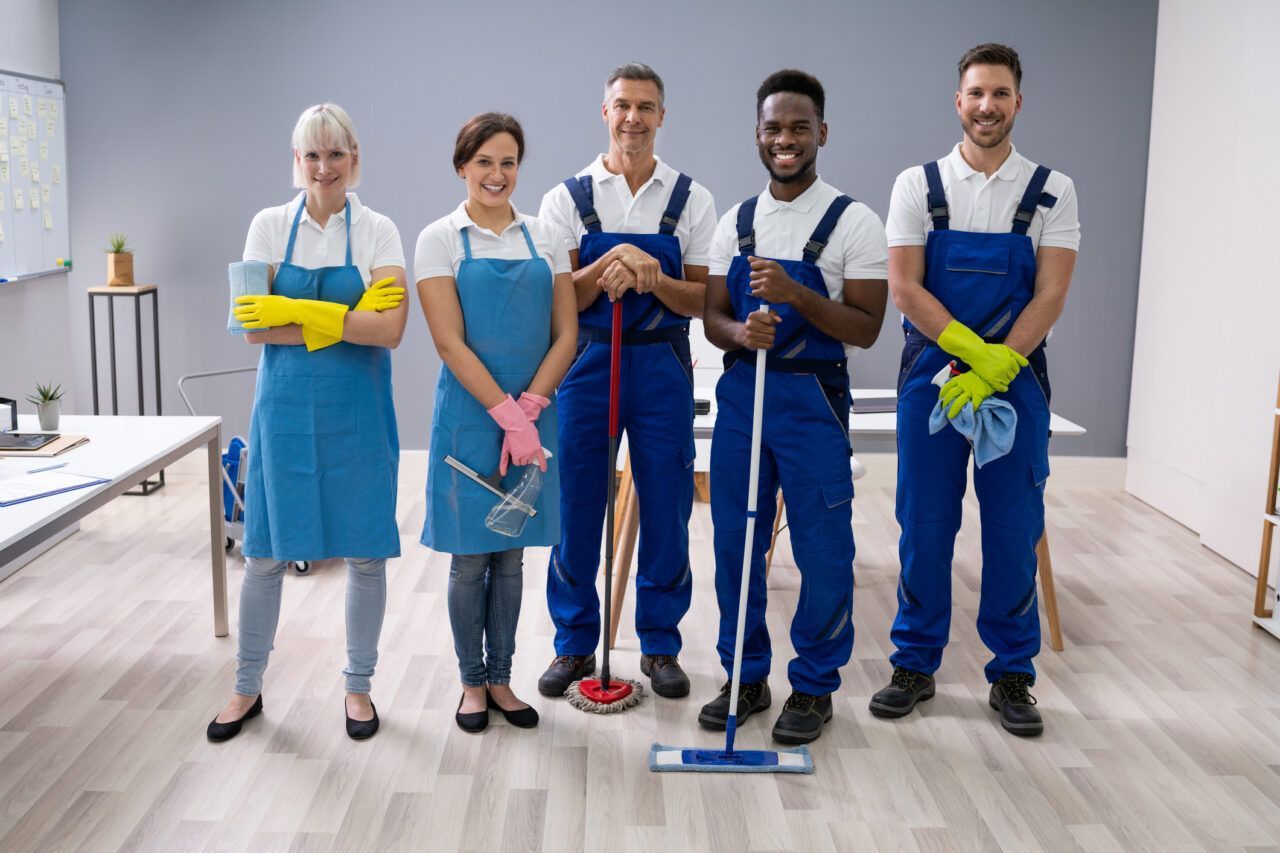 A group of cleaners are posing for a picture in an office.