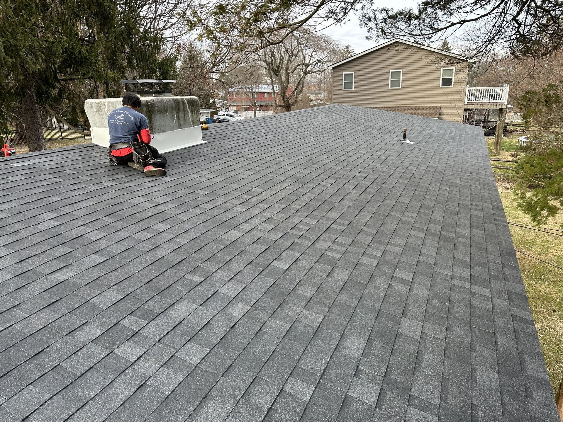 A man is kneeling on the roof of a house.